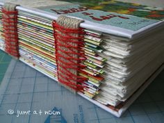 a stack of books sitting on top of a cutting board next to scissors and thread