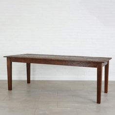 a wooden table sitting on top of a tile floor next to a white brick wall