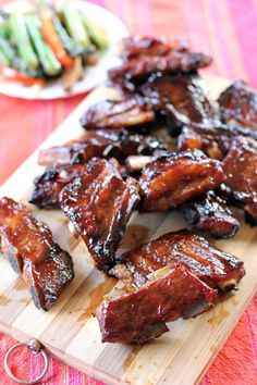 barbecue ribs on a cutting board with vegetables in the background