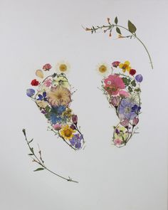 an arrangement of flowers arranged in the shape of footprints on a white surface with green stems