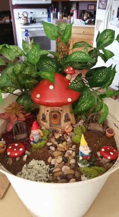 a potted plant with small gnomes and plants in it sitting on a table