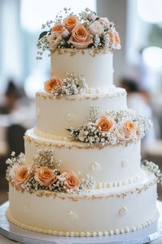 a three tiered wedding cake with flowers on top