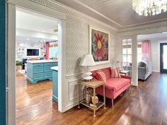 a living room filled with furniture and a chandelier hanging from the ceiling over a hard wood floor