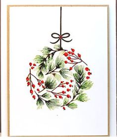 a christmas ornament with holly and red berries hanging from a string on a white wall