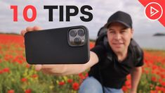 a man taking a photo with his cell phone in front of a field of flowers