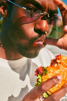 a man wearing glasses is eating a sandwich