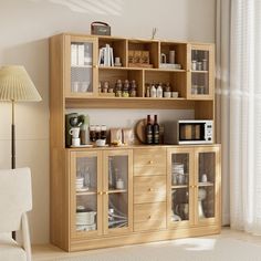 a wooden cabinet with glass doors and shelves in a living room next to a white chair