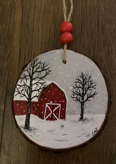 a wooden ornament with a red barn and trees on it