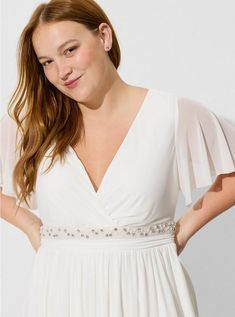 a woman is wearing a white dress and has her hands on her hips