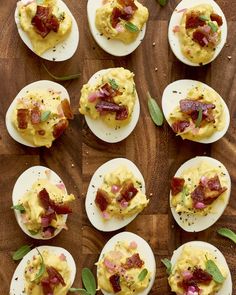 deviled eggs topped with bacon and herbs on a wooden cutting board, ready to be eaten