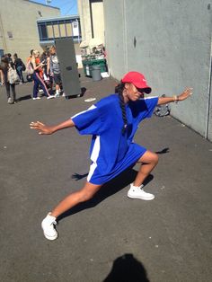 a woman in a blue dress and red hat is playing tennis on the court while people watch