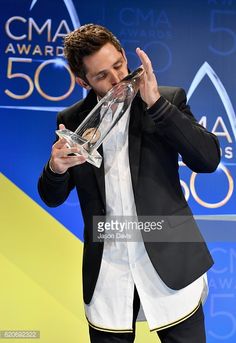 a man holding an award in his hand while standing on stage at the cma awards