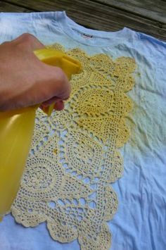 someone is using a yellow sprayer on a t - shirt that has doily