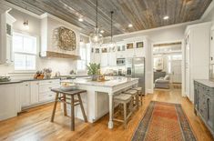 a large kitchen with white cabinets and wooden floors