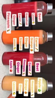 four orange, red and green juices are lined up on the wall next to each other