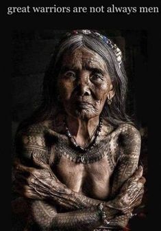 an old woman with tattoos on her chest and arms is sitting in front of a black background