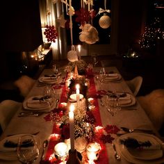 a dining room table set for christmas dinner with candles and decorations on the table top