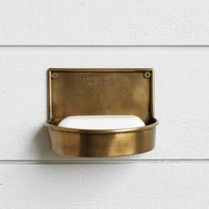 a gold toilet paper dispenser mounted to the side of a white wall