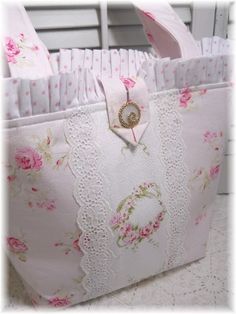 a pink flowered bag with white lace trimmings and flowers on the side