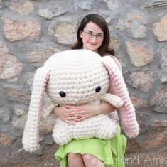 a woman is holding a crocheted bunny stuffed animal