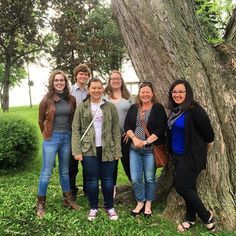 a group of people standing in front of a tree