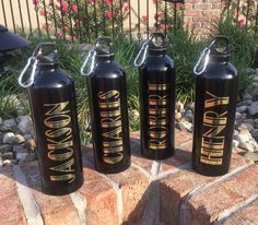 three black water bottles with gold lettering on them