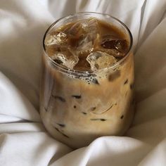 an iced drink in a glass sitting on top of a white blanket