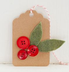 a tag with two red buttons and a green leaf on it sitting on a shelf