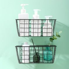 two metal baskets holding soap, lotion and hand sanitizers on a green wall