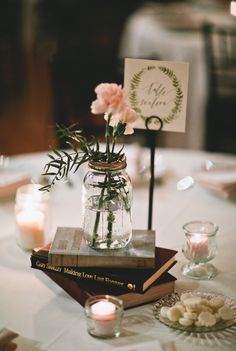 a table topped with books and flowers on top of a white table cloth covered table