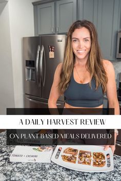 a woman standing in front of a kitchen counter holding a plate of food with the words, a daily harvest review on it