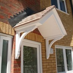 an awning attached to the side of a brick building with white doors and windows