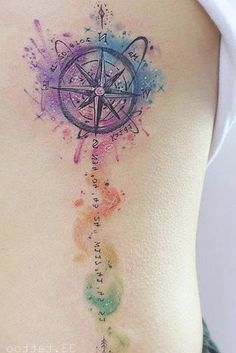 a woman's back with a compass tattoo on her stomach and watercolor paint splat