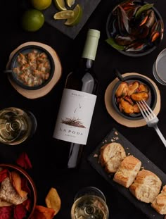 a bottle of wine sitting on top of a table next to plates and bowls filled with food