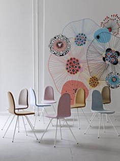 a group of chairs sitting next to each other in front of a wall with artwork on it