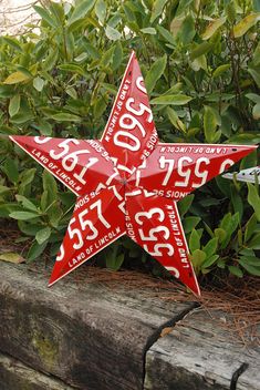 a red and white star shaped ornament sitting on top of a wooden fence