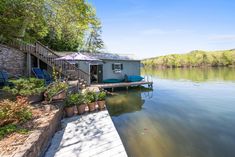 there is a boat dock on the water next to a house with an umbrella over it