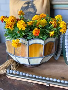 a potted plant with yellow and red flowers in it sitting on a wooden table