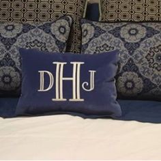 the monogrammed pillow on the bed is blue and has white letters that read,'dhj '