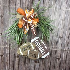 a football ornament hanging on the side of a wooden fence with an orange and white bow