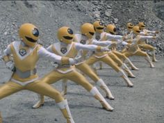 a group of people dressed in yellow and white uniforms standing on one leg with their arms outstretched