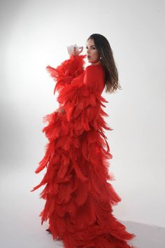 a woman in a long red dress drinking from a cup