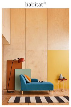 a blue couch sitting on top of a wooden floor next to a yellow and white wall