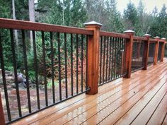 a wooden deck with metal railings and trees in the background