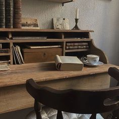 a wooden desk topped with books next to a chair and table filled with books on top of it