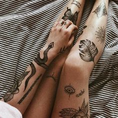 two people with tattoos on their legs laying in bed next to each other and holding hands together