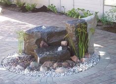 a rock fountain in the middle of a brick walkway