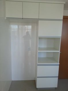 an empty room with white cupboards and shelves next to a person standing in the doorway