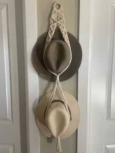 two hats are hanging on the wall next to a door with a hat hanger