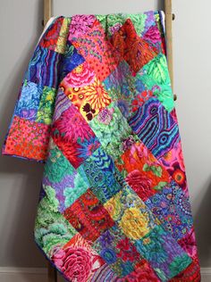 a multicolored quilt hanging on a wooden chair